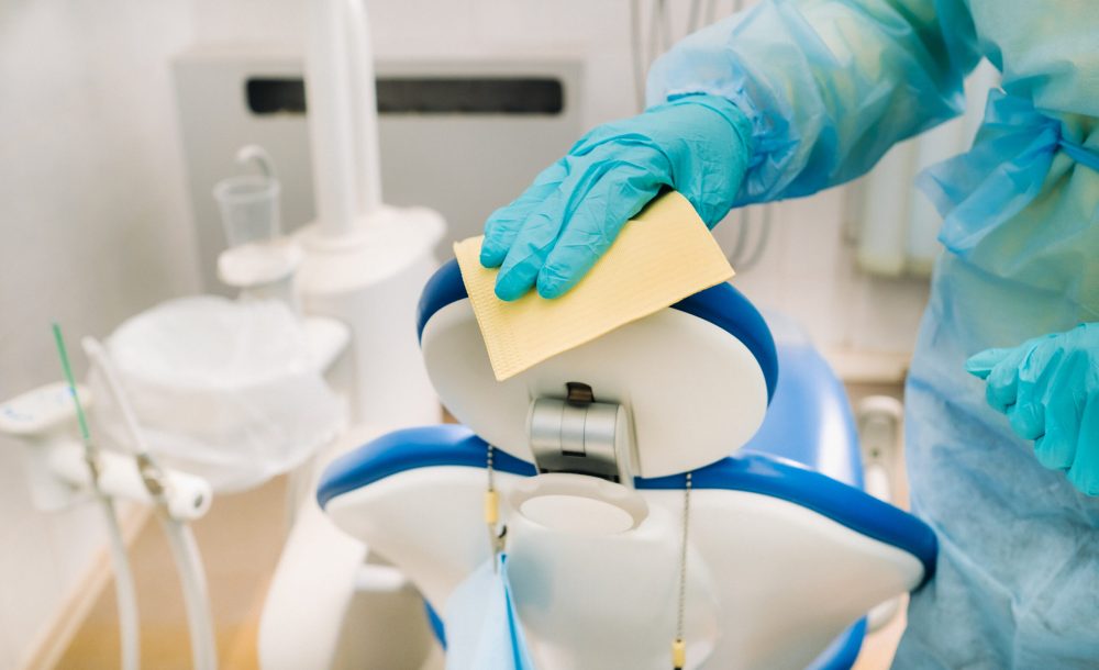 A nurse disinfects work surfaces in the dentist's office..
