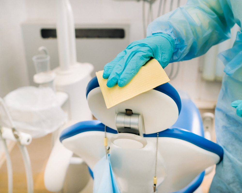 A nurse disinfects work surfaces in the dentist's office..