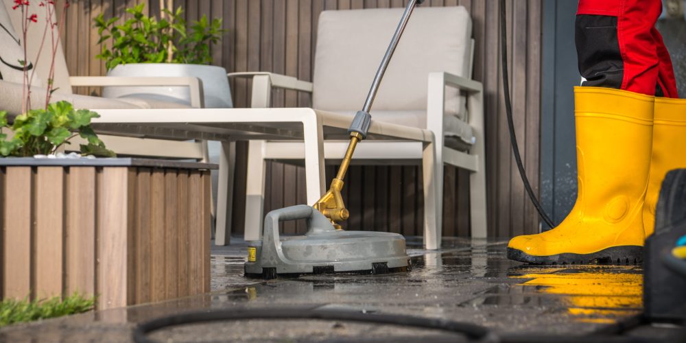 Home Owner Cleaning His Concrete Surface Patio with a Pressure Washer.