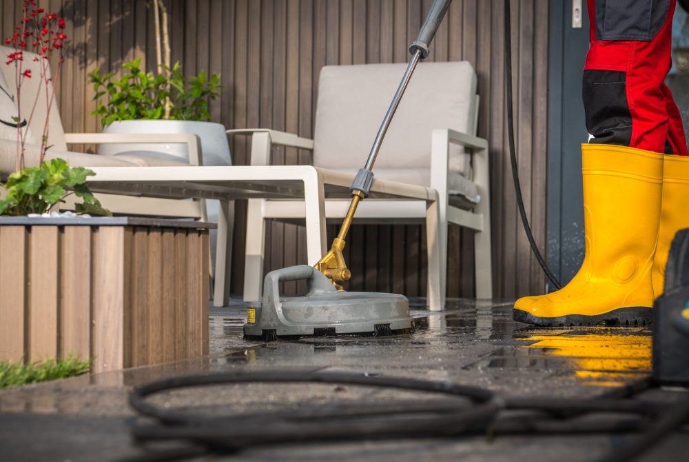 Home Owner Cleaning His Concrete Surface Patio with a Pressure Washer.